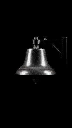 Vintage metal bell on a black background. Black and white photo.の素材