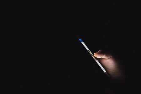 Mobile phone in hand on black backgroundの写真素材
