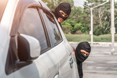 Two robbers are secretly behind the car. Planning a robberyの写真素材