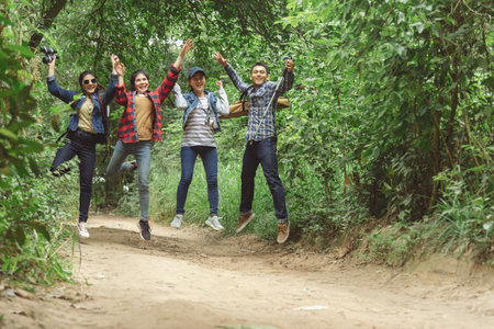 Happy smiling friends with musical instruments jumping in the forest outdoors