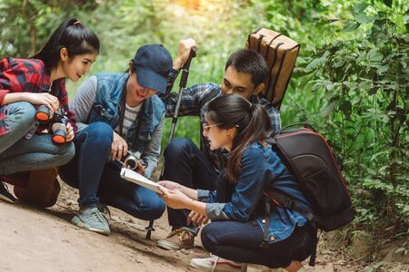 Group of smiling friends walking with backpacks in woods - adventure, travel, tourism, hike and people concept. Young Men And Women On Hike Tourists Adventure Activityの写真素材