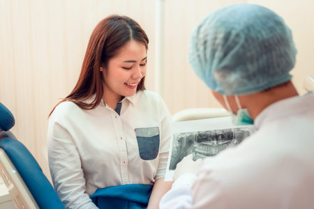 Senior male dentist in dental office talking with female patient and preparing for treatment.
