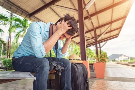 Asian depressed traveler waiting at train station after mistakes a trainの写真素材