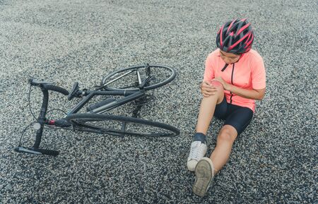 Young Woman With Pain In Knee When Fallen Down From Bicycleの写真素材