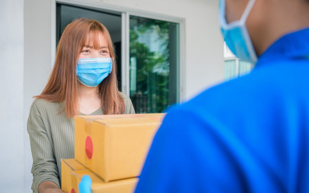 Smart food delivery service man in red uniform handing fresh food to recipient and young woman...