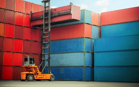 Forklift truck handling cargo shipping container box in logistic shipping yard with cargo container stack in background
の写真素材