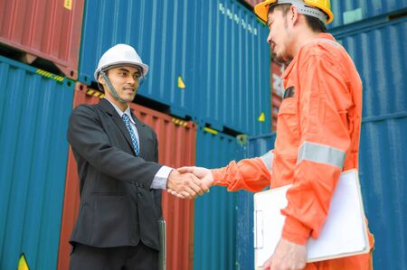 Technician and engineer shake hand in cargo container area with concept collaborative working.の写真素材