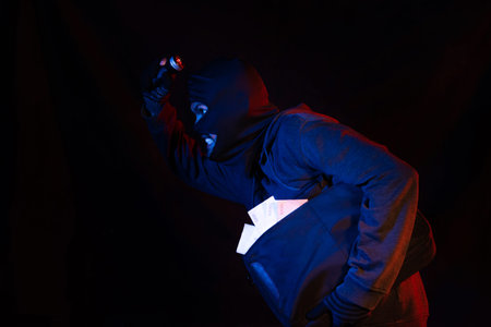 Thief robbed bank and is carrying full bag of money. Isolated on black background.