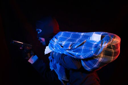 Thief robbed bank and is carrying full bag of money. Isolated on black background.の写真素材