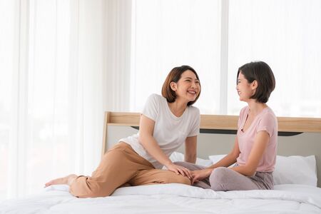 Asian lesbian LGBT Couple warm hug on bed in bedroom with laughing moment,love win concept,beautiful attractive happiness momentの写真素材