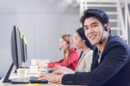 Attractive young man working in a call center with his colleagues
