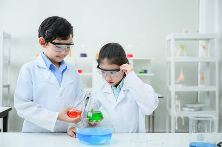 Little scientists adding color dye into beakers