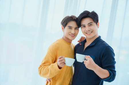 Happy gay couple with coffee at table indoors