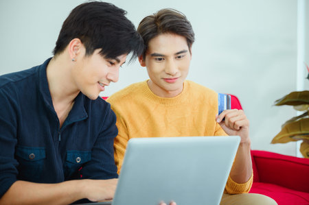 Asian homosexual couple in pajamas shopping online with computer notebook in the bed.Concept LGBT...
