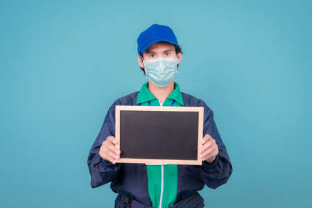Delivery service man holding cardboard boxes on blue background copy spaceの写真素材