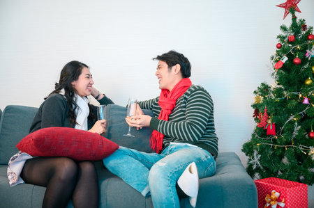 Young couple warming up with plaid and hot drinks sitting on the terrace of the modern house in the mountains durnig the winter holidaysの写真素材