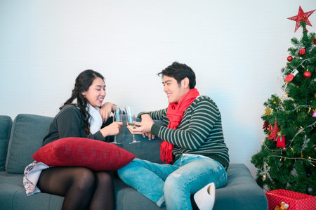 Young couple warming up with plaid and hot drinks sitting on the terrace of the modern house in the...