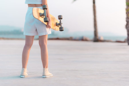 Young women hold surf skateboard with beach sunset background,Sport and fun on vacation.