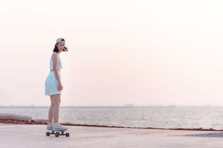 Asian women surf skate or skateboard outdoors on beach miami sunset.の写真素材