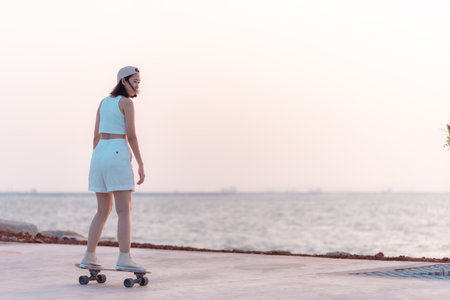 Asian women surf skate or skateboard outdoors on beach miami sunset.の写真素材
