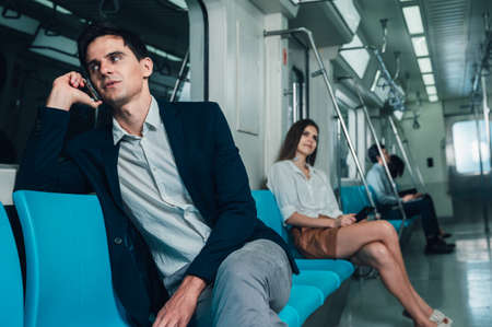 Business man using a phone to work on a subway train in the middle of the nightの写真素材