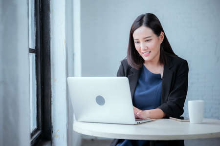 Young businesswoman rejoicing after sales surpass their target Check results from laptopの写真素材