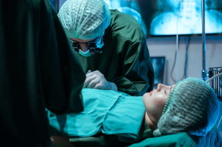 The medical team is collaborating on cosmetic surgery in the operating room.の写真素材