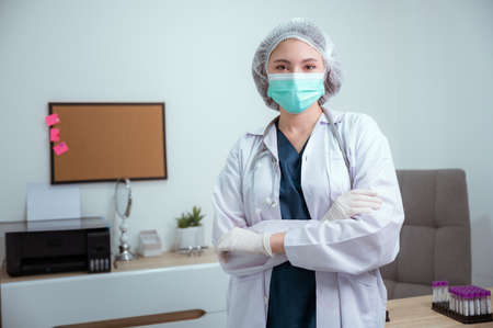 Portrait of doctor in scrubs. A female doctor in a protective cap and face mask in safety measuresの写真素材