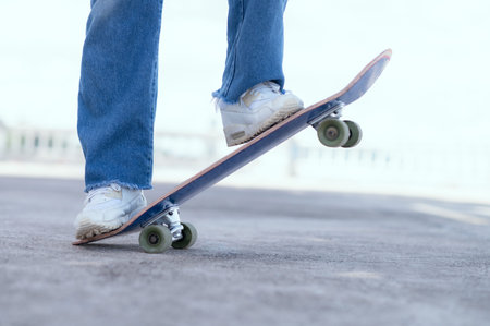 Skateboarder doing a trick at the city's street in sunny day. Young man in sneakers and cap riding...