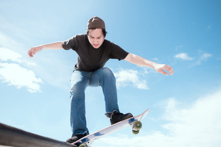 Teenager skateboarder does an ollie trick on background of blue sky gradient