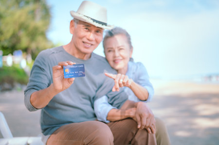Elderly Asian couple holding a credit card with a smile Health insurance for the elderly, retireesの写真素材