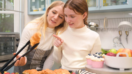 Mother-daughter looked at each other happily after tasting the treats they had cooked together in...