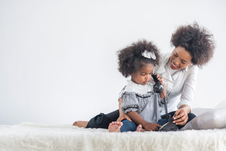 African full family sit on bed in living room play with little kids parents tickles children daughter happy timeの写真素材