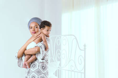 Black mother is raising a child in the bedroom in the morning.の写真素材