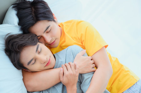 Male couple cuddling in bed early morning LGBQ Asian gay couple huggingの写真素材