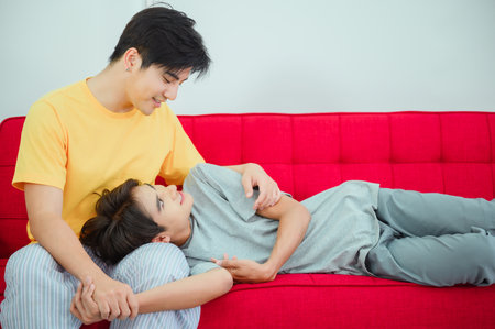 Gay Asian couple cuddling and playing on the sofa in the room in the morning gender diversityの写真素材
