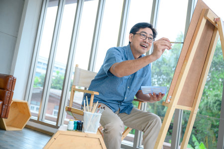 Smiling elderly man painting a vacation at homeの写真素材