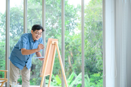 Smiling elderly man painting a vacation at homeの写真素材