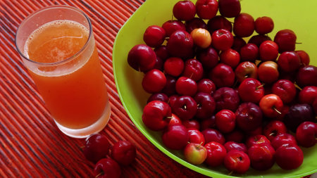 Cherries and a glass of cherry juice on a wooden tableの写真素材