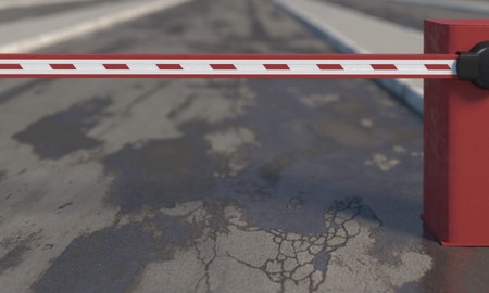 Red lowered road barrier close-up on a blurred background of wet cracked asphalt road with pits and...