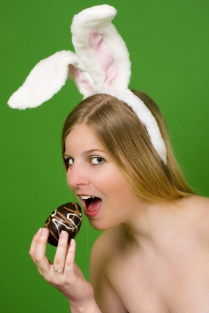 Young blonde woman with bunny ears ready to eat an Easter eggの写真素材