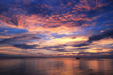 Amazing coloured skies with local fishing boat heading outの写真素材