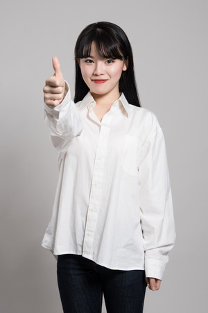 Studio portrait of twenties Asian woman expressing pleasure and happiness with fingerの写真素材