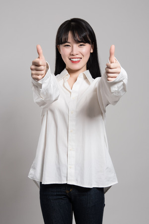 Studio portrait of twenties Asian woman expressing pleasure and happiness with fingerの写真素材