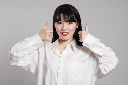 Studio portrait of twenties Asian woman expressing pleasure and happiness with fingerの写真素材