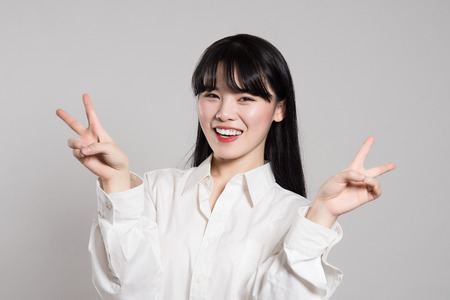 Studio portrait of twenties Asian woman expressing pleasure and happiness with fingerの写真素材