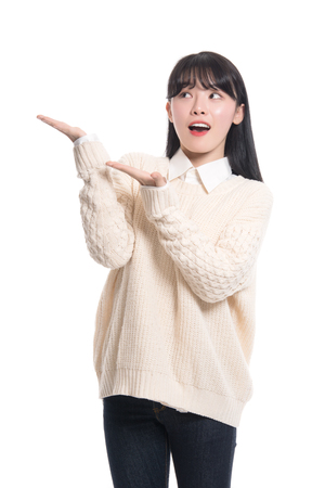 A studio portrait of a twenties Asian woman pointing at something and confidently introducingの写真素材