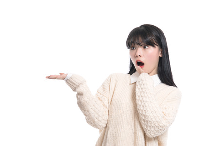 A studio portrait of a twenties Asian woman pointing at something and confidently introducingの写真素材