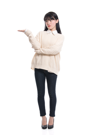 A studio portrait of a twenties Asian woman pointing at something and confidently introducingの写真素材