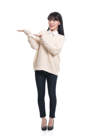 A studio portrait of a twenties Asian woman pointing at something and confidently introducingの写真素材